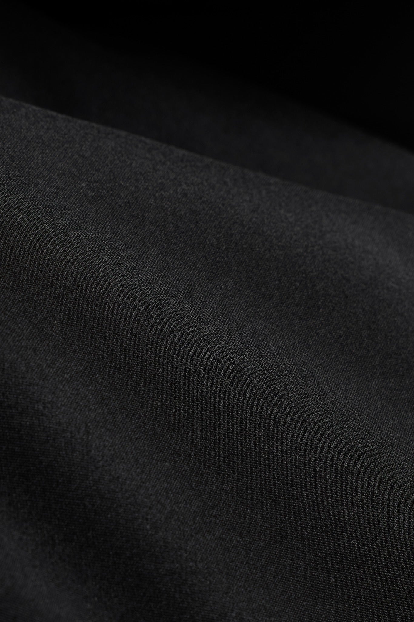 Close-up texture of the black water-repellent shell fabric on the CASPARA Aurora Puffer Vest.